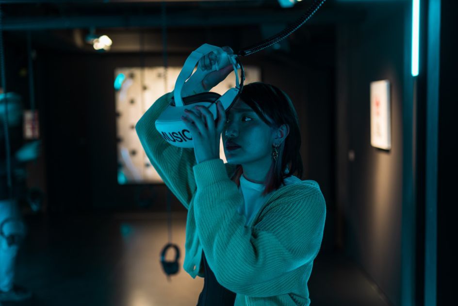 Besucherin, die VR-Brille mit der Aufschrift "MUSIC" aufsetzt, in der Ausstellung im MOMEM